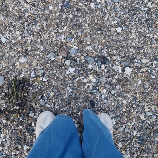 Füße auf Steinboden beim Strandspaziergang – ein Symbol für Achtsamkeit, Erdung und bewussten Minimalismus im Alltag.